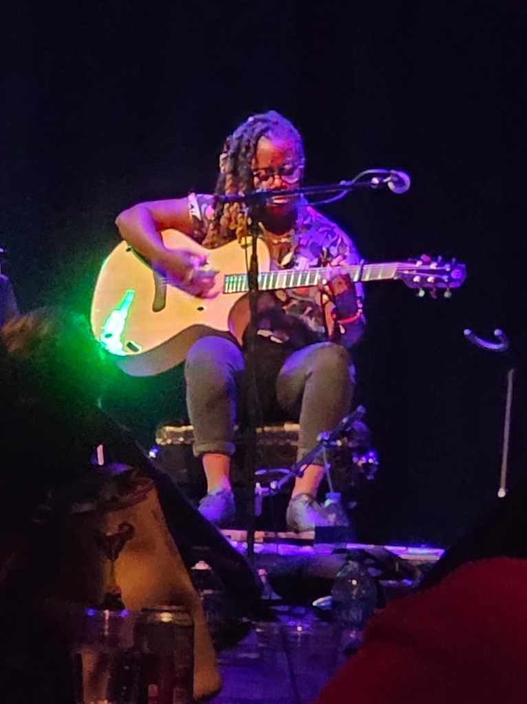 Dark skin woman sitting, playing acoustic guitar