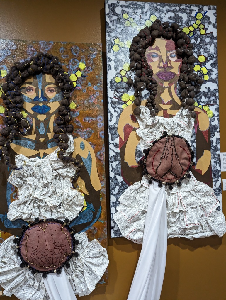 Mixed-media collages of two women on canvases, connected by a large cloth ribbon.